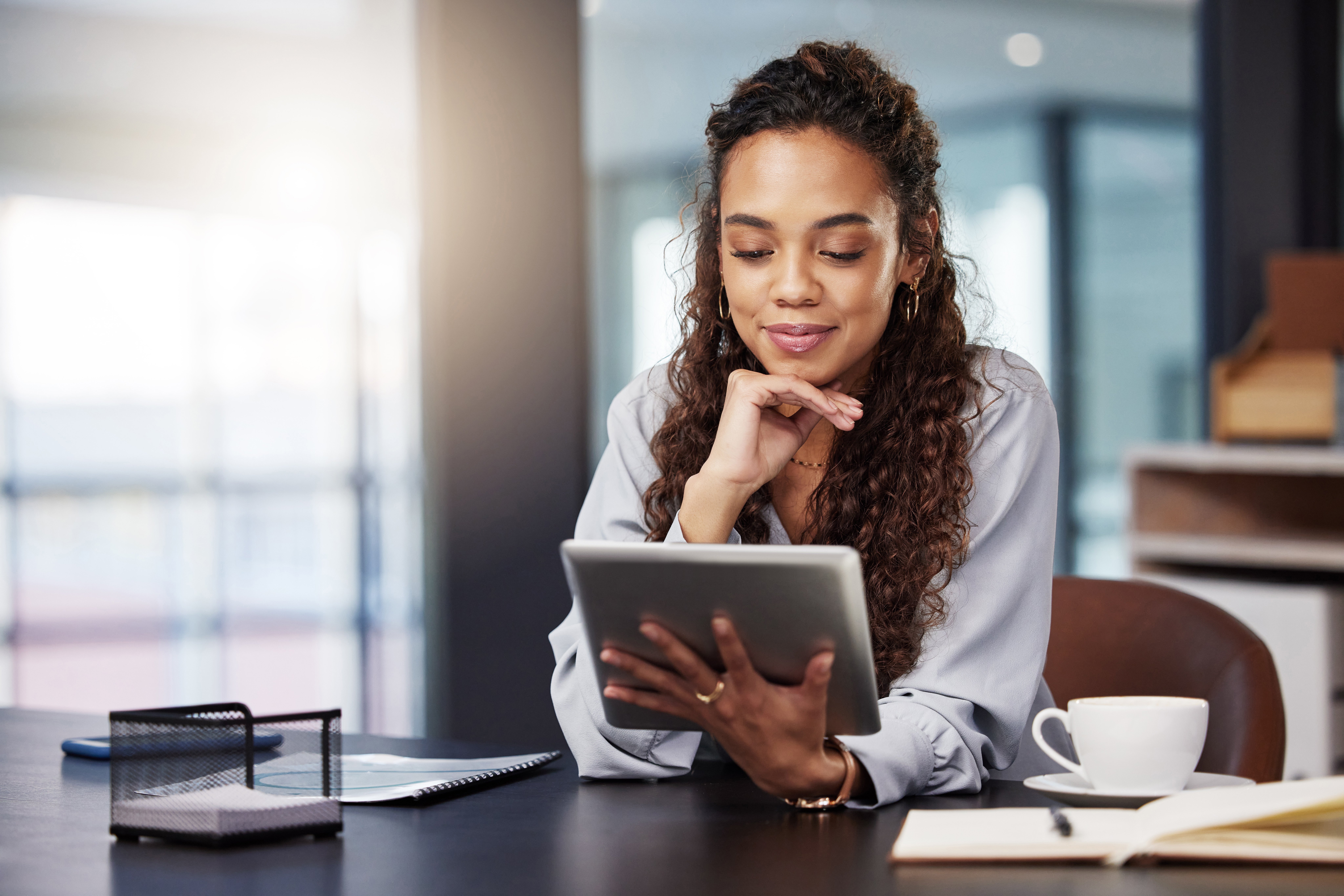 Woman with chin on right hand and tablet held in left hand
